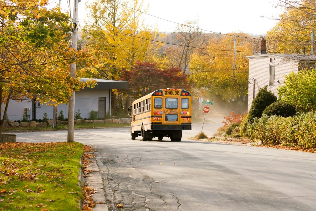 A yellow school bus driving down the street. Photo by Jan Budomo on Unsplash